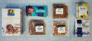 from left to right then top to bottom, cinnamon crunch cereal, Enjoy Life chocolate chunks, salted sesame sticks, raisins, roasted sunflower seeds, roasted cashews, dried blueberries